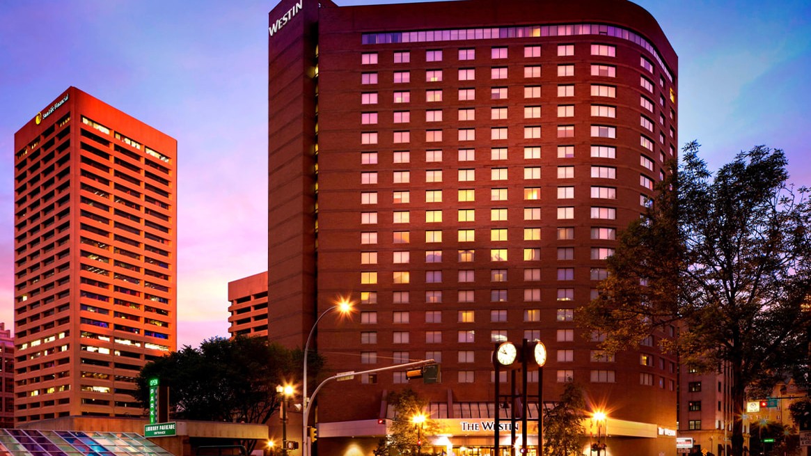 Evening view of The Westin hotel and surrounding buildings with illuminated windows and streetlights.
